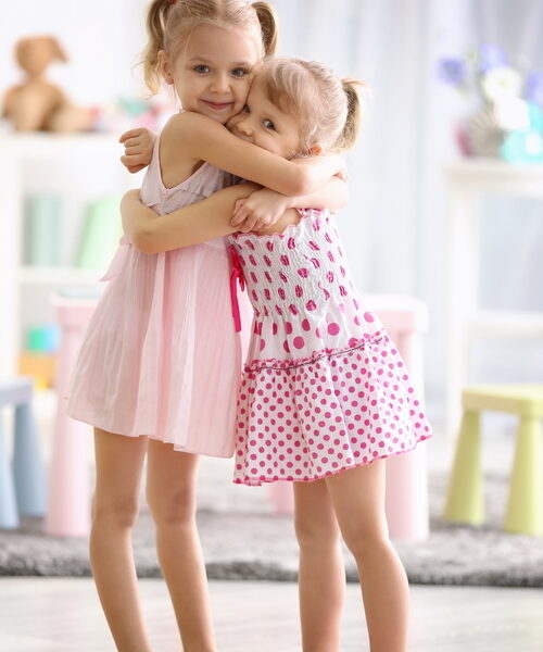 Cute little girls embracing at home